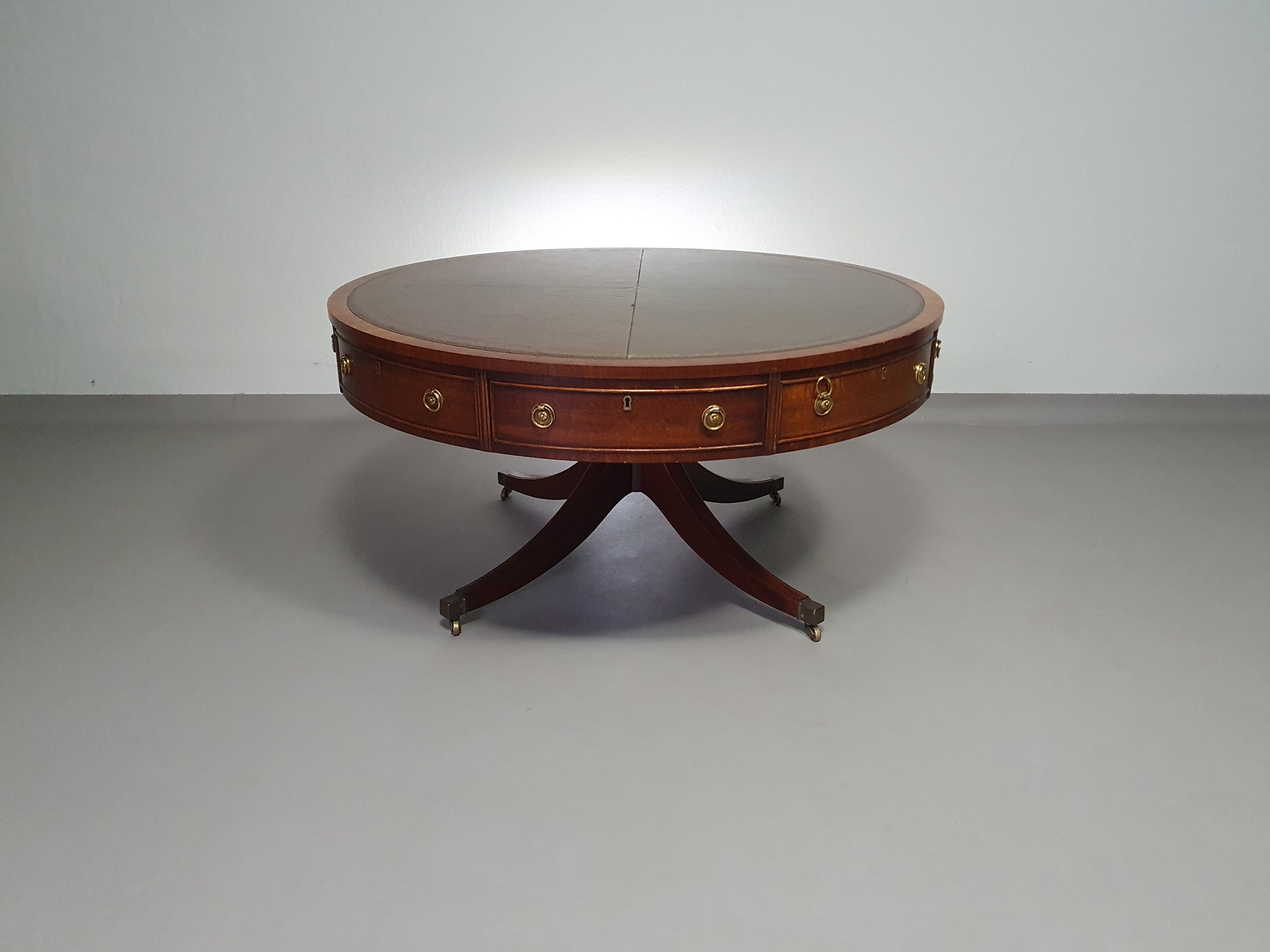 Mahogany Victorian " Heldense " Coffee table / Drum table with leather top on brass wheels. '80s